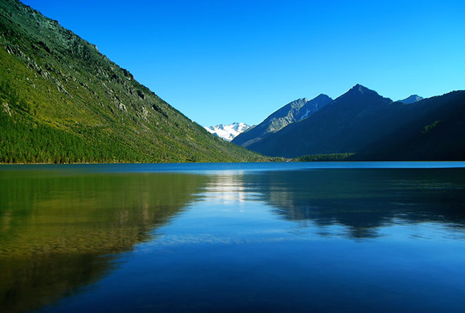 A picture of a tranquil lake in Switzerland with mountains and calm inviting water