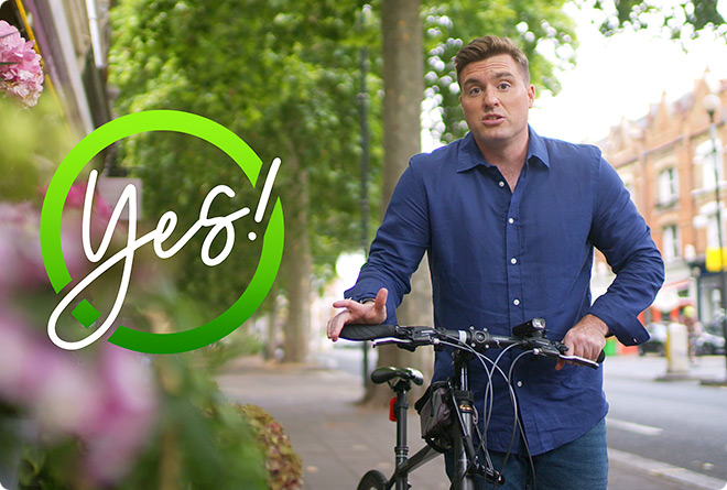 A real Jane Plan customer pushing his cycle along a London road with a Yes! graphical device next to him